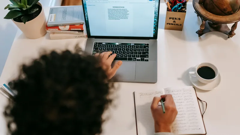 A writer types on a laptop over coffee at home, representing AI-assisted, brand-voice-consistent content creation.