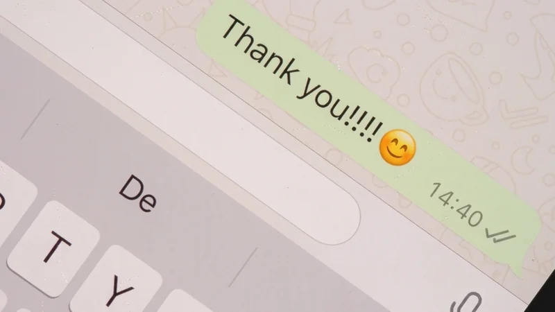 Close-up of a WhatsApp chat on a phone: a green sent bubble reads “Thank you!!!!” with a smiling emoji, stamped 14:40 with two grey ticks, above the keyboard.